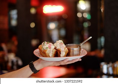 Woman's Hand Holding Lobster Roll In White Plate , Close-up