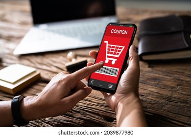 Woman's Hand Holding Mobile Phone With Shopping Coupon