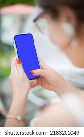 Woman's Hand Holding A Mobile Phone With A Vertical Green Screen