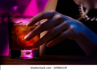 Woman's Hand Holding Old Fashioned Glass With Cold Cocktail Against Blurred Night Club Background