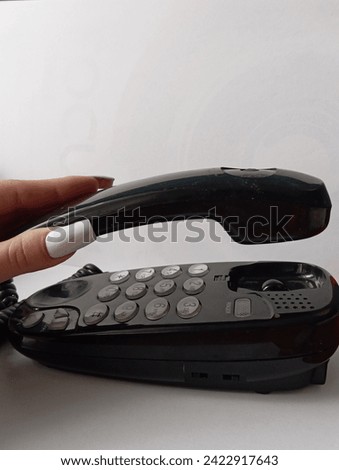 A woman's hand is holding an oldstyle phone on the white background 