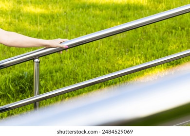 woman's hand holding onto the metal staircase railing. metal stair handrail. woman climbing stairs - Powered by Shutterstock