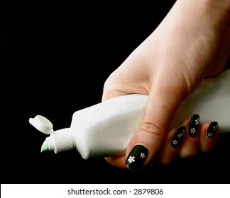 Woman's Hand Holding An Opened Toothpaste Tube On The Black Background