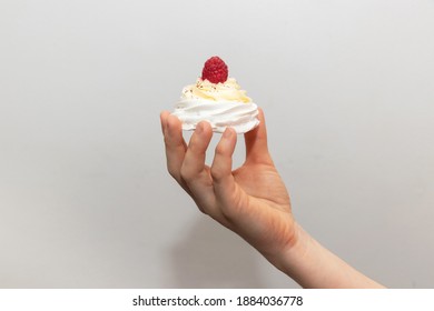 A Woman's Hand Holding A Pavlova Cake On A Light Background