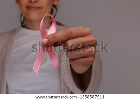Woman's hand holding pink ribbon isolated.