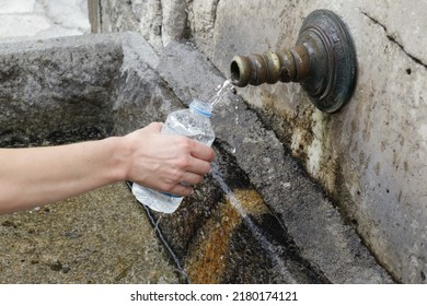 Woman`s Hand Holding Plastic Water Bottle And Refill With Fresh Spring Water 