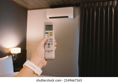 woman's hand holding remote airconditioner in bedroom at night - Shutterstock ID 2149667163