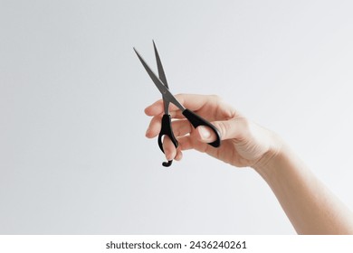 Woman's hand holding scissors on white background with cpyspace