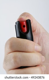 A woman's hand holding a small bottle of pepper spray