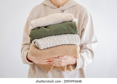 Woman's hand holding a stack of clothes. Clothes Donation, Renewable Concept.Preparing Garment at Home before Donate. Woman packs clothes for a donation or for moving - Shutterstock ID 2095993648