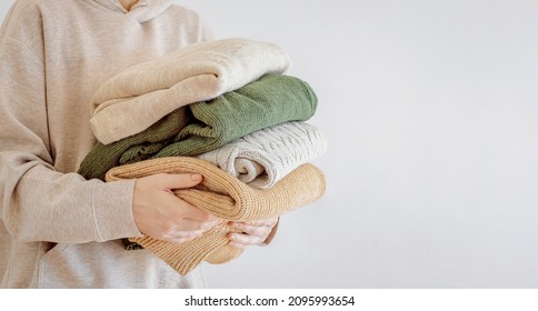 Woman's hand holding a stack of clothes. Clothes Donation, Renewable Concept.Preparing Garment at Home before Donate. Woman packs clothes for a donation or for moving - Shutterstock ID 2095993654