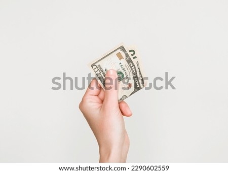 woman's hand holding a ten dollar bill