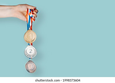 Woman's hand holding three medals (gold,silver,bronze).concept of award and victory.copy space - Powered by Shutterstock