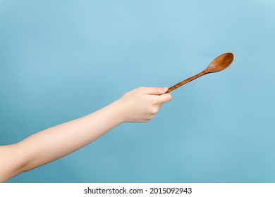 Woman's Hand Holding A Wooden Spoon In One Hand