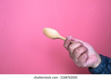 Woman's Hand Holding A Wooden Spoon Isolated, On Red Background