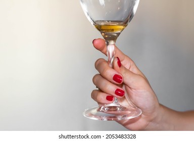 A Woman's Hand Holds Up An Almost Empty Wine Glass, Close Up