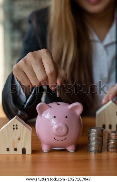 A woman\'s hand holds a\
coin to manage money and Plan your savings to buy the best home for\
your family, ideas for savings, growth, economy, business and\
investing.