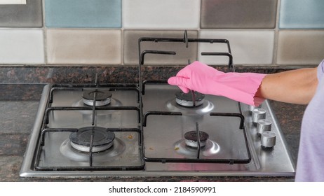 A woman's hand holds the grate from the gas stove for cleaning - Shutterstock ID 2184590991