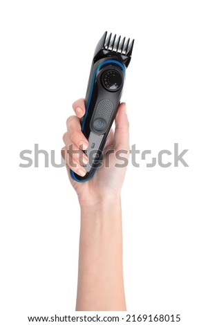 A woman's hand holds a hair clipper. Trimmer. The hairdresser