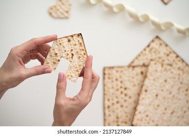 Woman's hand holds Matzah shape of house. Traditional of Jewish Holiday on Passover. Home symbol of lovely family. top view, layout. real estate agency