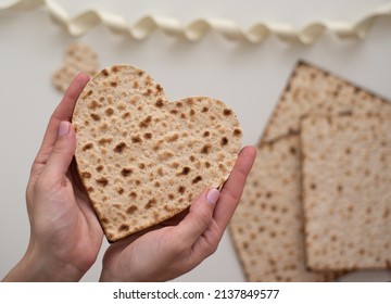 Woman's hand holds Matzah shape of heart. Traditional of Jewish Holiday on Passover. Home symbol of lovely family. top view, layout. love and care. Gift for lovers. Feeling in love and blissful life