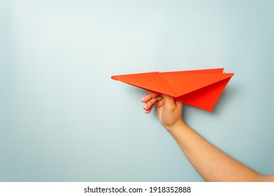 A woman's hand holds a red paper airplane on a pale blue background. copy space - Powered by Shutterstock