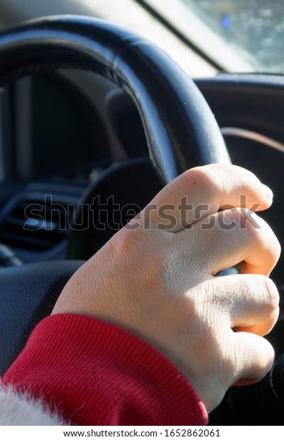 woman\'s hand holds\
the steering wheel of a\
car