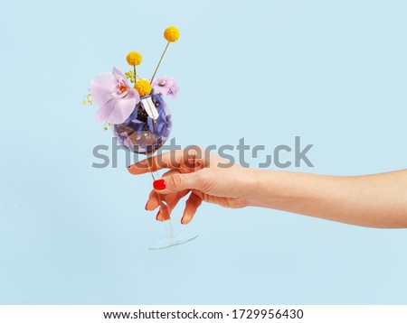 Woman's hand holds wine glass filled with flowers