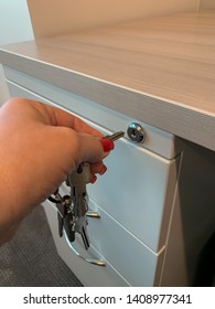 Woman's Hand Inserting Key Into File Cabinet Keyhole.