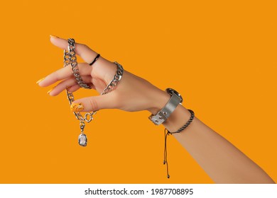 Womans hand with jewelry accessories over orange background