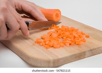 Woman's hand with a knife cuts the carrot on the wooden board in the kitchen. Healthy eating and lifestyle. - Powered by Shutterstock