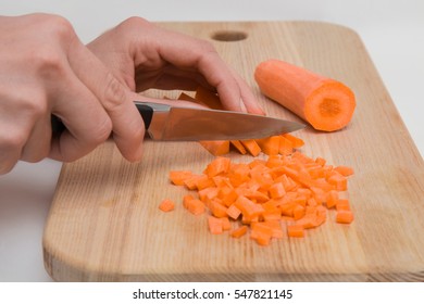 Woman's hand with a knife cuts the carrot on the wooden board in the kitchen. Healthy eating and lifestyle. - Powered by Shutterstock