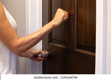 Woman's Hand Knocking On A Brown Wooden Door And Turning A Doorknob, Medium Shot, Side View, Horizontal Photo