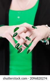 Woman's hand and long nails   bright green manicure and bottles nail polish