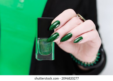 Woman's hand and long nails   bright green manicure and bottles nail polish