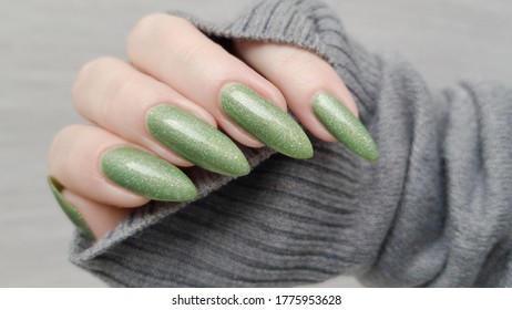 Woman's hand and long nails   green manicure and bottles nail polish