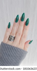 Woman's hand and long nails   green manicure and bottles nail polish