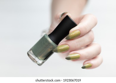Woman's hand and long nails   light   dark green manicure and bottles nail polish 	