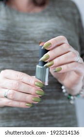 Woman's hand and long nails   light   dark green manicure and bottles nail polish	