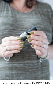 Woman's hand and long nails   light   dark green manicure and bottles nail polish	