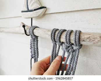 A Woman's Hand Making Crochet From Grey Cotton Yarn Wall Hanging With A Boat Sculpture On It