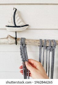 A Woman's Hand Making Crochet From Grey Cotton Yarn Wall Hanging With A Boat Sculpture On It