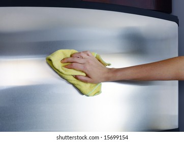 Woman's Hand With Microfiber Cloth Polishing A Stainless Steel Fridge Door