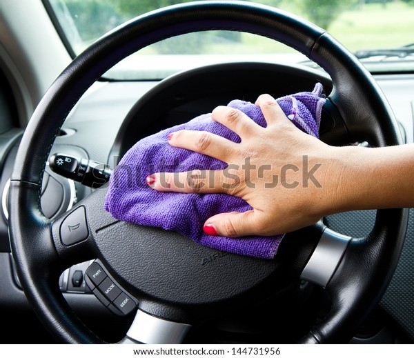 Woman\'s hand with microfiber cloth polishing wheel of\
a car