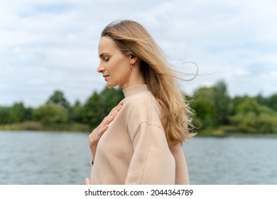 Woman's hand on her chest while doing breathing exercises and meditating. Harmony concept - Shutterstock ID 2044364789