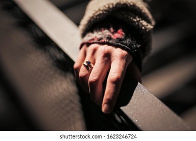 Woman's hand on a railing with a ring on her finger.
