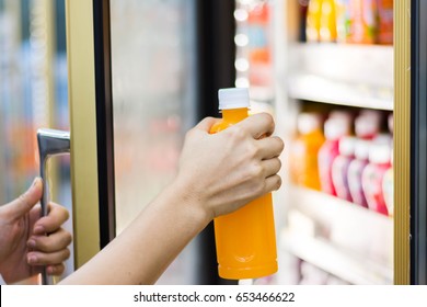 woman's hand open convenience store refrigerator shelves and pick product