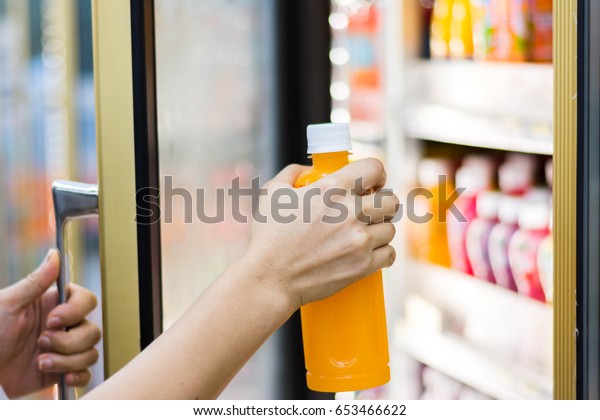 woman\'s hand open convenience store refrigerator\
shelves and pick\
product