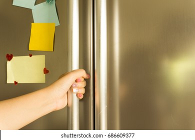 Woman's Hand Open Refrigerator With Note On The Door