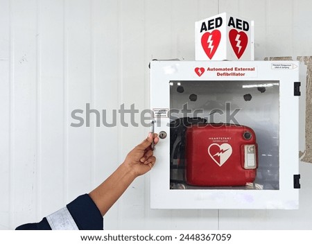 woman's hand opens AED (automatic external defibrillation) box
